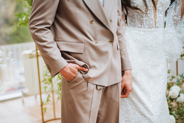 A man in a suit with a blazer is standing next to a woman in a wedding dress