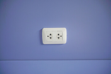 Old electric plug on blue wall.