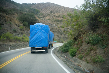 Truck with tarpaulin passing country road.