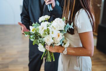 A man with a microphone and a woman with white flower bouquet