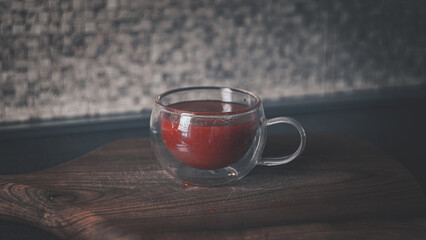 Glass cup with tomato juice on a wooden cutting board