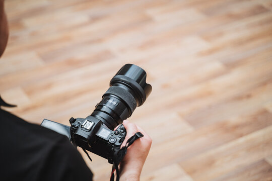 Hand holding camera on hardwood floor with camera accessory