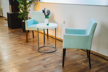 Two chairs next to a table with a vase of flowers in a building