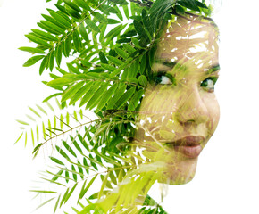 A double exposure woman's portrait merged with a photo of green leaves
