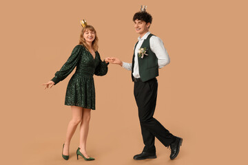 Happy prom couple with crowns dancing on beige background © Pixel-Shot