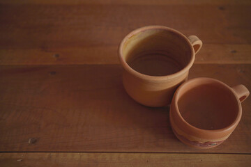 Empty earthenware mug on wooden table background.