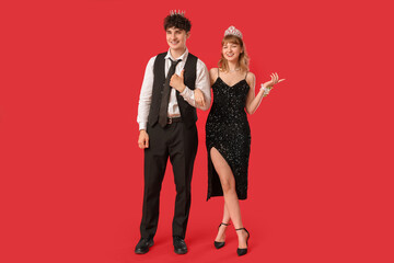 Happy prom couple with crowns on red background