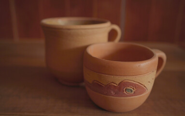 Empty earthenware mug on wooden table background.