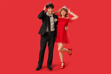 Happy prom couple in crowns on red background