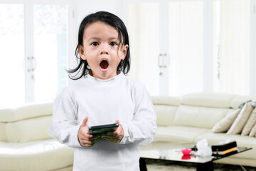 Cute girl with shocked face holding a mobile phone