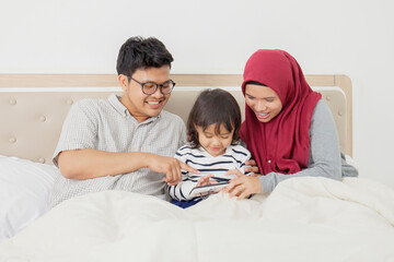 family looking at a mobile phone on bed