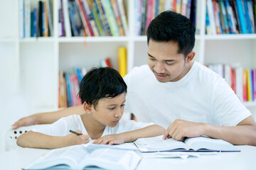 Picture of young man guiding his son to study with bookshelf background