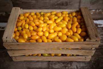Fresh yellow cherry tomatoes in the wooden box.