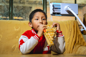 latin boy learning to play the panpipes by looking at his cell phone - music concept