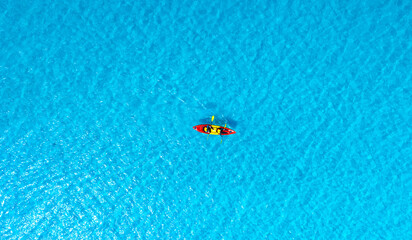 Aerial view of a woman and a young man kayaking on clear blue waters at Andaman Island. She does...