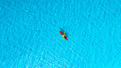 Aerial view of a woman and a young man kayaking on clear blue waters at Andaman Island. She does water sports activities.