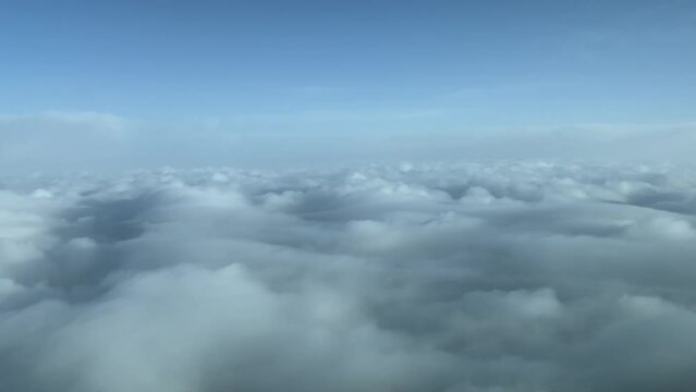 Exclusive aerial shot from a plane cockpit while flying over a blanket os stratus clouds. Immersive pilot POV. Daylight, blue sky. 4K 60FPS