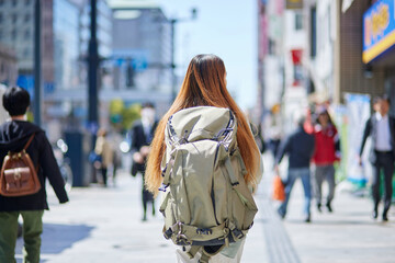 バックパックを背負って都会を歩く女性の外国人旅行者