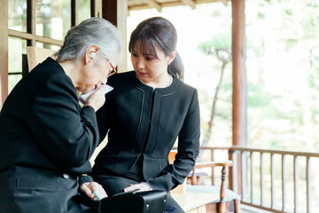 お葬式で泣く喪服を着た遺族の高齢者女性と若い日本人女性
 - obrazy, fototapety, plakaty