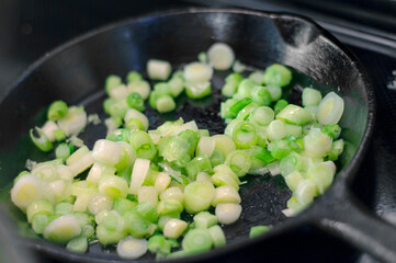 Green onions cooking in cast iron pan
