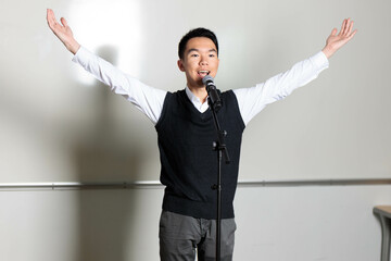 Orator makes a happy gesture, arms outstretched at a public speaking event