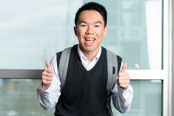 A business school student in formal wear with a smile gestures thumbs up excitedly