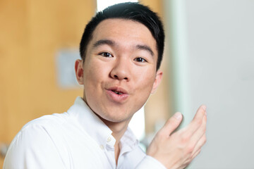 A student in a white dress shirt is gesturing and talking casually to the camera