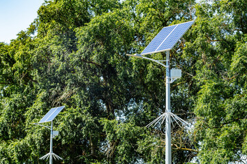 Lamp post with solar panel system on road with blue sky and trees. Autonomous street lighting using...