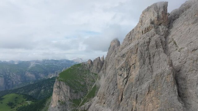 Cinematic aerial footage of a drone soaring close to the Selva mountain range near Passo Gardena, Dolomites. Italy. The drone flies forward, revealing the mountains covered in clouds. LuPa Creative.