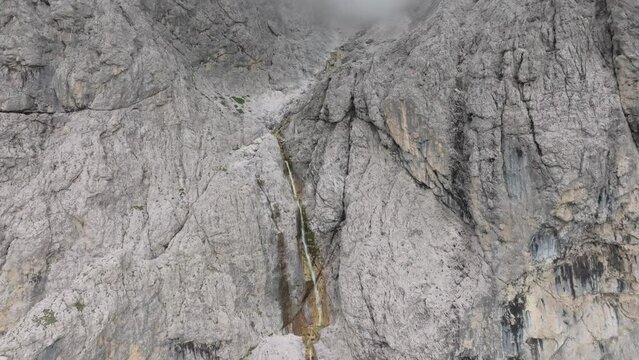 Cinematic descending aerial view of the Murfreit waterfall near Passo Gardena. The drone is slowly folowwing the stream of water. Selva di Val Gardena, Dolomites, South Tyrol, Italy. LuPa Creative.