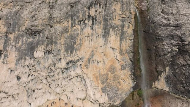 Cinematic ascending aerial view of the Murfreit waterfall near Passo Gardena. The drone is flying up until it reaches the clouds. Selva di Val Gardena, Dolomites, South Tyrol, Italy. LuPa Creative.