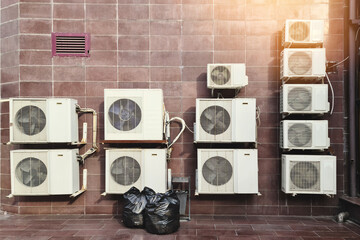 Numerous air conditioning units are affixed to the exterior wall of the building. Urban industrial backdrop.