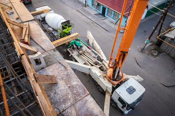 Concrete pump truck transfers concrete from a mixer truck to pour the floor at a construction site, top view.