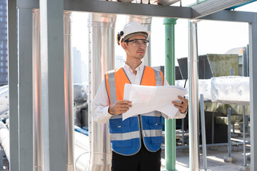 Portrait Asia male engineer in protective workwear is performing a conducts system check with use paperwork at rooftop building	