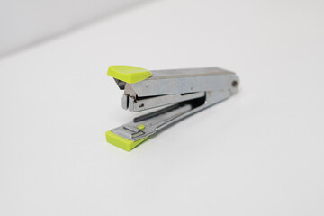 Silver colored stapler with green handle made of stainless steel