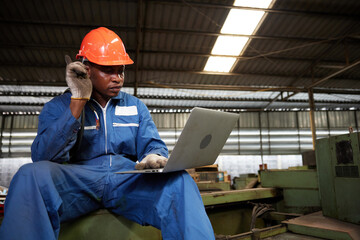 male african workers or technician using laptop computer and pointing pose in the factory