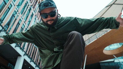 Low angle view of hipster pose in hip hop style surrounded by mall view. Portrait of sporty asian...