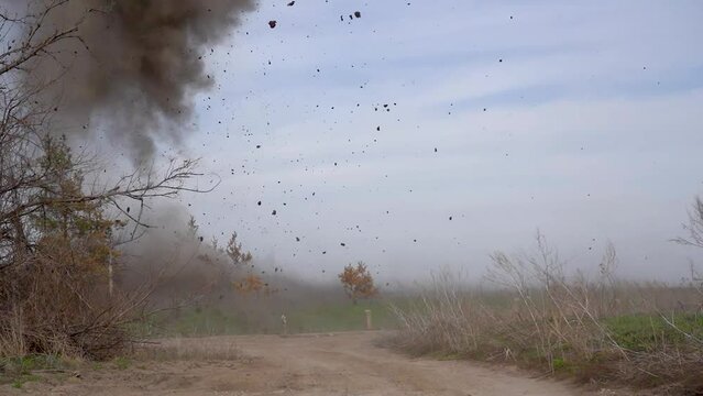 Explosion of an anti-tank mine in a field. Projectile hit. A bright flash, smoke and clods of falling earth. Fighting during the war. Mine danger.