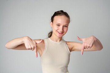 Young Woman in Tank Top Pointing Down in studio