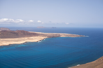 Views of the island of La Graciosa from the viewpoint of El Rio. Turquoise ocean. Blue sky with big white clouds. Caleta de Sebo. Town. volcanoes. Lanzarote, Canary Islands, Spain