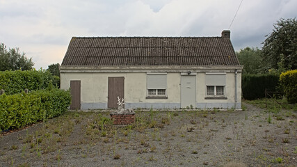 Decaying abandoned house with empty front garden in a village in Flanders, Belgium 