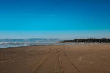 Sehr breiter Sandstrand in Neuseeland auf der Südinsel mit blick aufs Wasser und Spuren von Autos im Sand