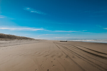 Sehr breiter Sandstrand in Neuseeland auf der Südinsel mit blick aufs Wasser und Spuren von Autos im Sand
