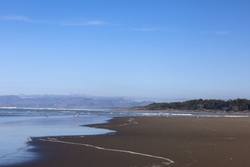 Sehr breiter Sandstrand in Neuseeland auf der Südinsel mit blick aufs Wasser und Spuren von Autos im Sand