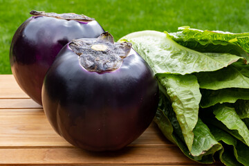Fresh ripe purple globe Violetta eggplants vegetables and green Romaine lettuce from Sicily,...