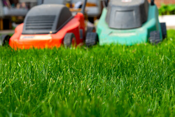 Fototapeta premium Seasonal maintenance works in garden, lawn movers in action, green grass cutting, lawn care, English lawn