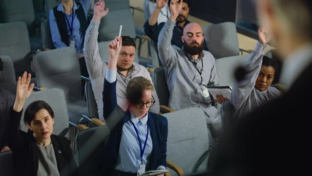 Close up of president, politician or activist giving interview for television or media from the stage in the conference hall. Diverse journalists raise hands and ask questions during press campaign.