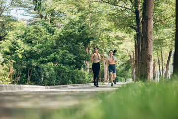 two Asian women engaging in physical activity within an urban park.