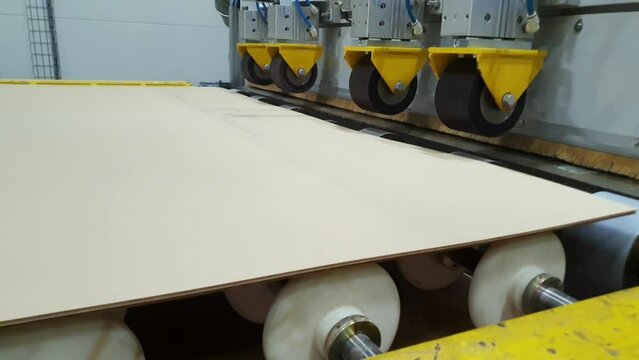 Laminated insulation cardboard production process. Raw materials for laminated cardboard. Electric cardboard travels along the conveyor line. Automated line in production. Roller conveyor