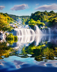 Skradinski Buk waterfall reflected in the calm waters of Visovacko lake. Splendid morning scene of...